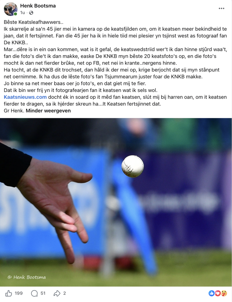 Close-up of a hand releasing a cricket ball in midair on a blurred cricket field background.