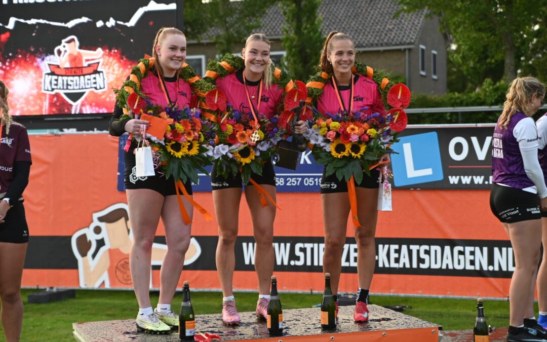 Three female athletes stand on a podium with bright bouquets and medals after a competition, smiling at the camera.
