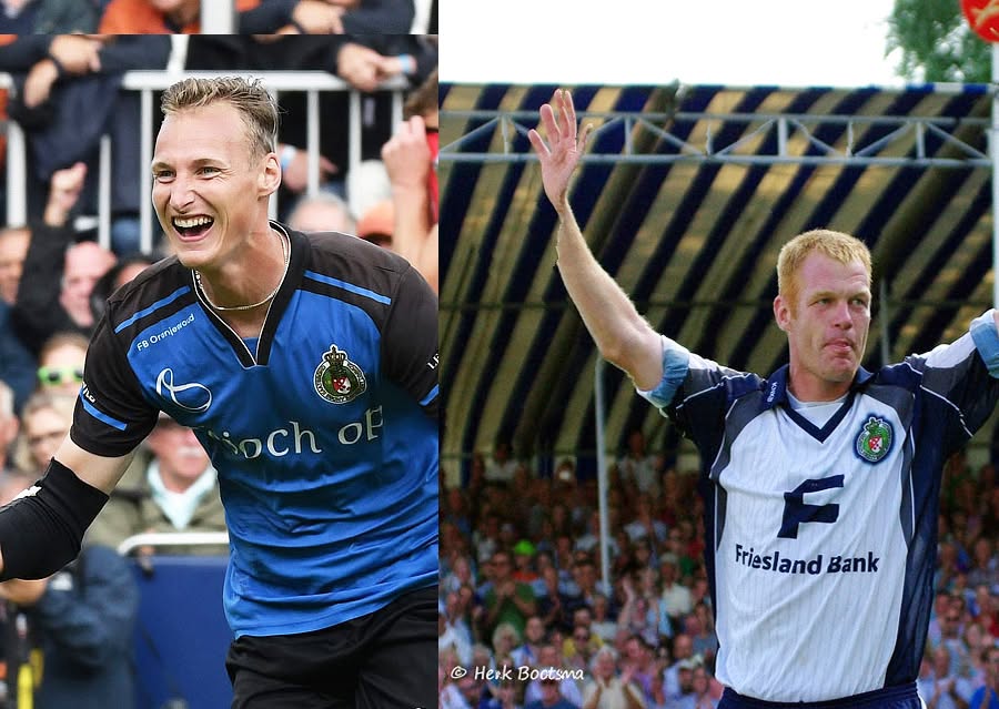Tjisse_Chris - kaatsnieuws.com Two male field hockey players celebrate, one in blue-black kit on the left and one in white kit on the right, with a cheering crowd behind them.